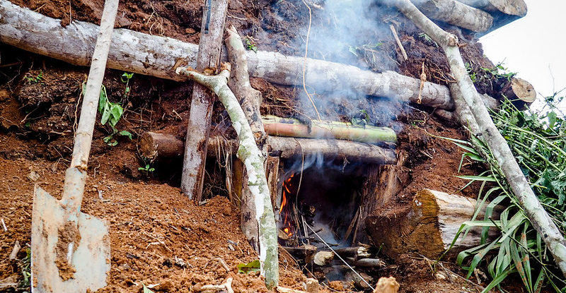 A mound under which smoke from smoldering charcoal burns