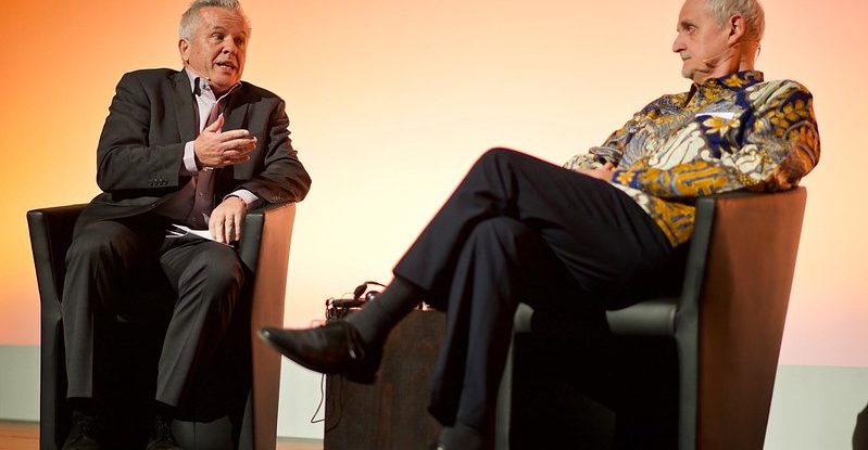 Two men in easy chairs engage in conversation