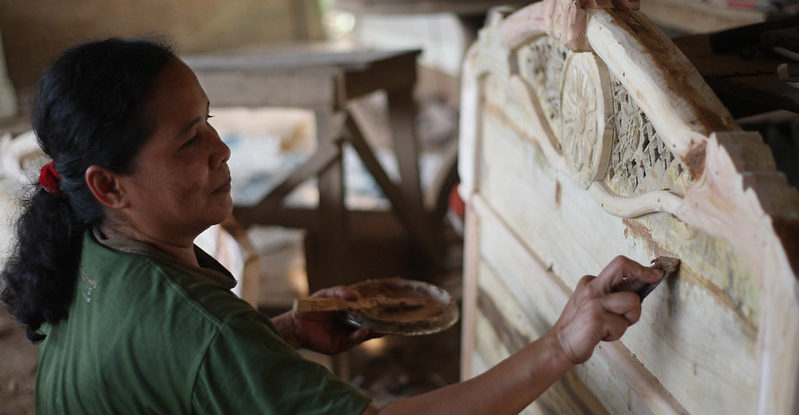 A woman applies filler to gaps in wood