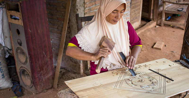 Woman chisels a design into wood