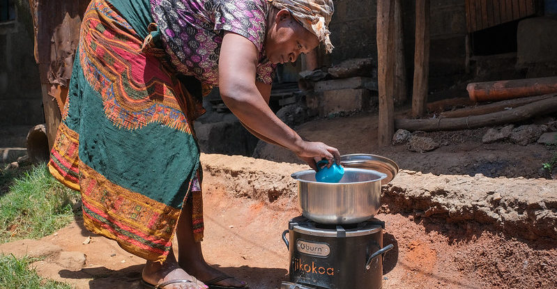 A woman cooks in a pot on an outdoor stove